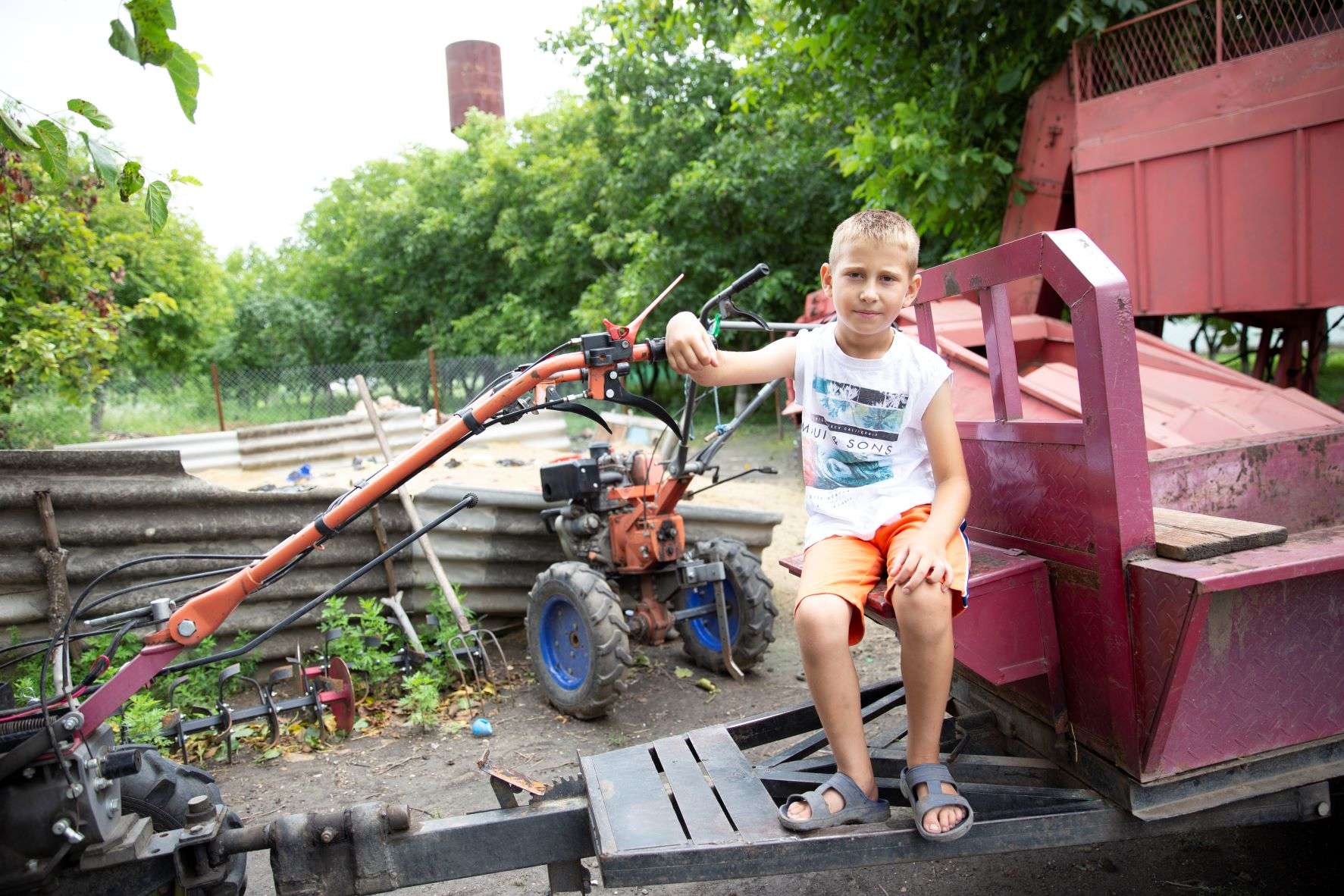 Un băiat din Moldova care stă pe echipament agricol