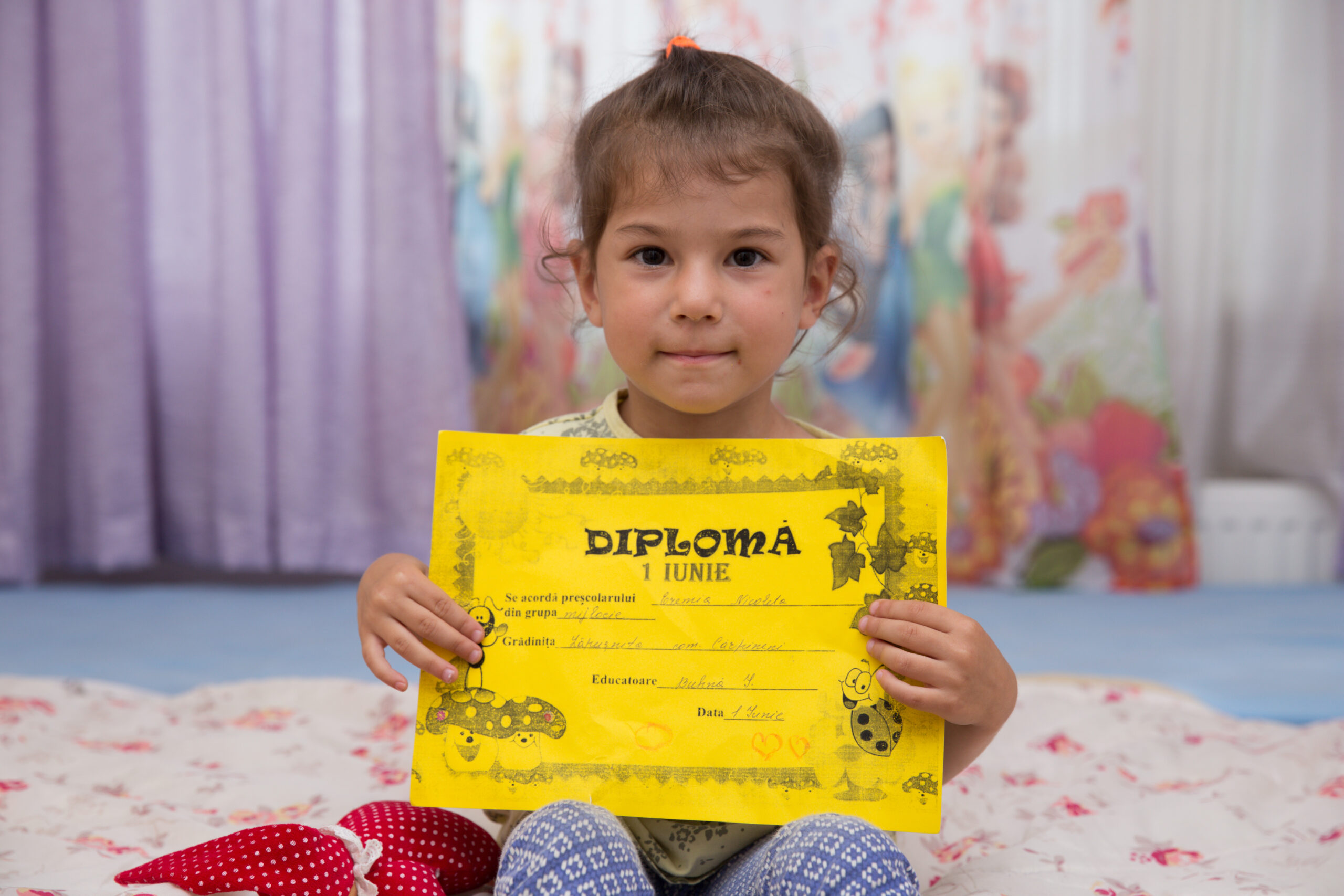 Natalia din Moldova își ține în mână diploma de școală.