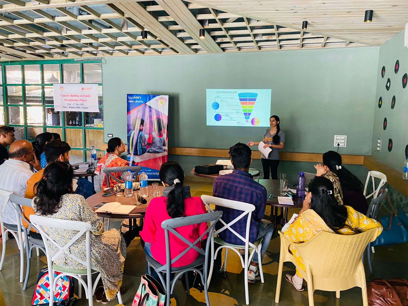 a woman presenting to a crowd with a powerpoint slide behind her