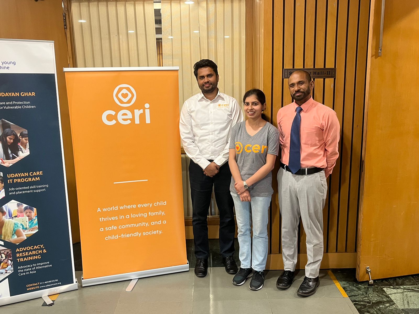 two men and one woman stand next to an orange sign that says ceri